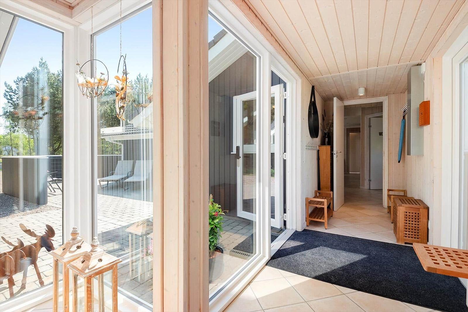 Eingangsbereich mit Holzwand, Tür und Blick auf die Terrasse.