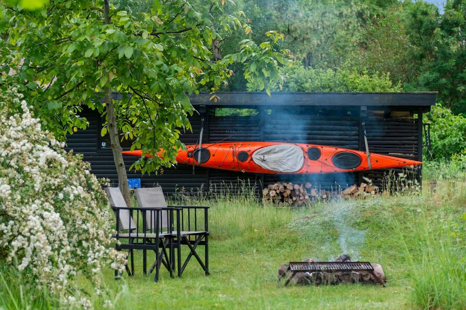 Ein Strohhut liegt auf einem Holztisch. Im Hintergrund sind graue Sitzkissen zu sehen.