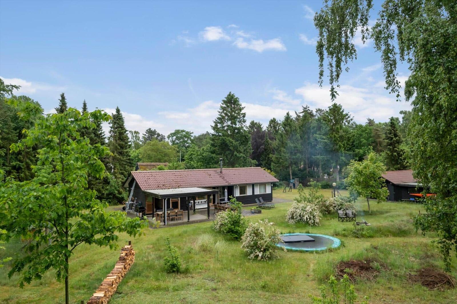 Schlafzimmer mit Bett, Kleiderständer und Fenster zum Wald.