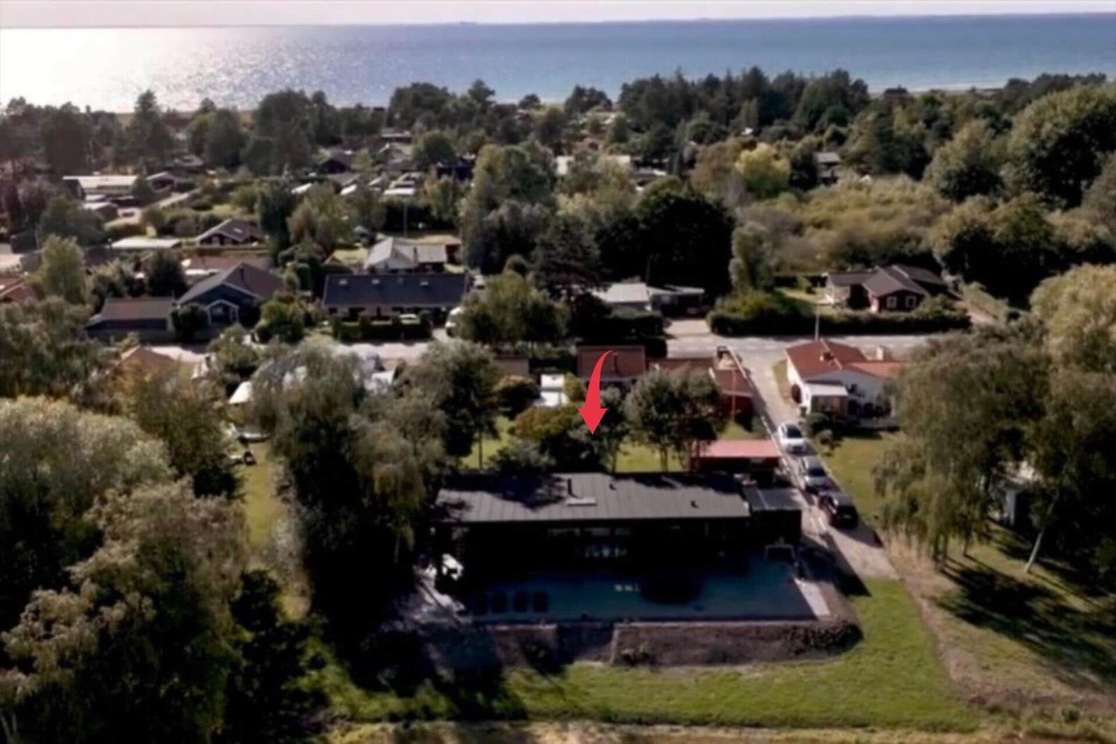 Haus mit Pool und Garten, umgeben von Bäumen, nahe dem Meer.