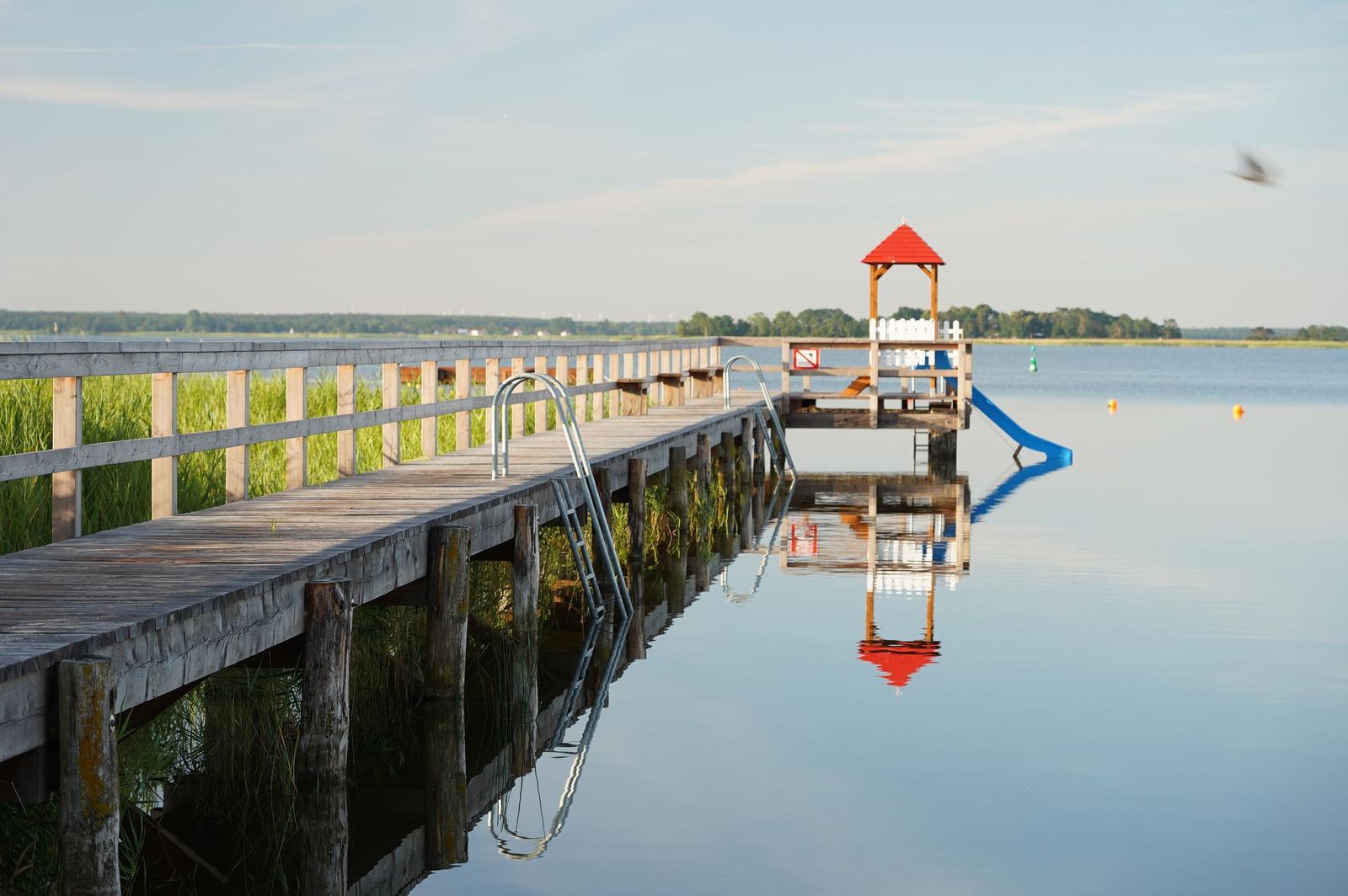 Holzboot mit Namen Wieck/Darb liegt am Wasser und ist mit Seilen und Steuerruder ausgestattet.