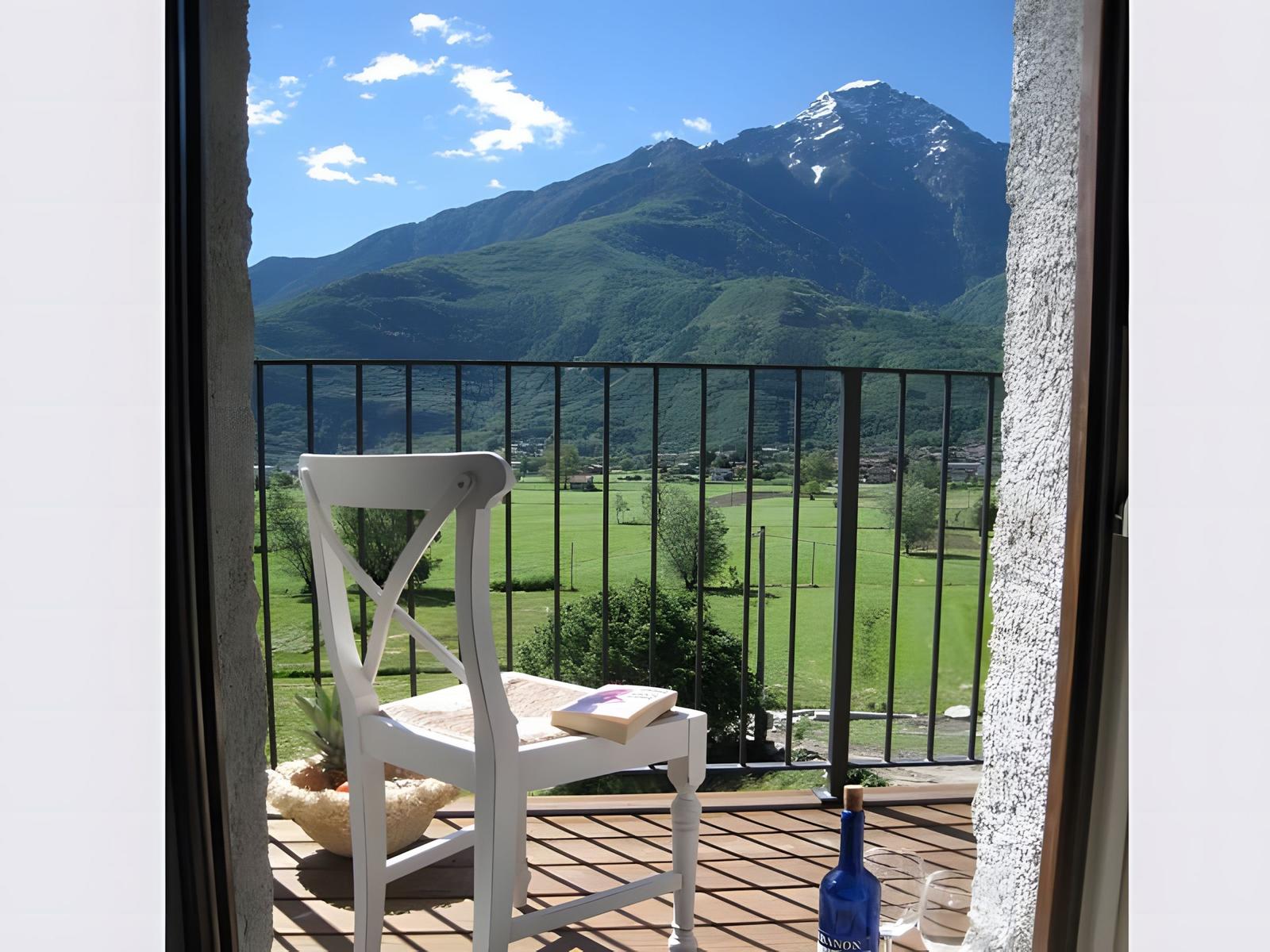 Steinhaus mit Lavendelbeet und Schild Borgo Erliob vor grüner Landschaft.