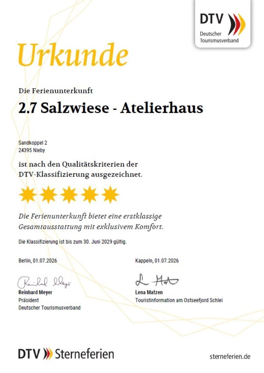Ein Bett mit weißer Bettwäsche und Holzgestell. Neben dem Bett steht ein Nachttisch mit Lampe und Wasserflasche.