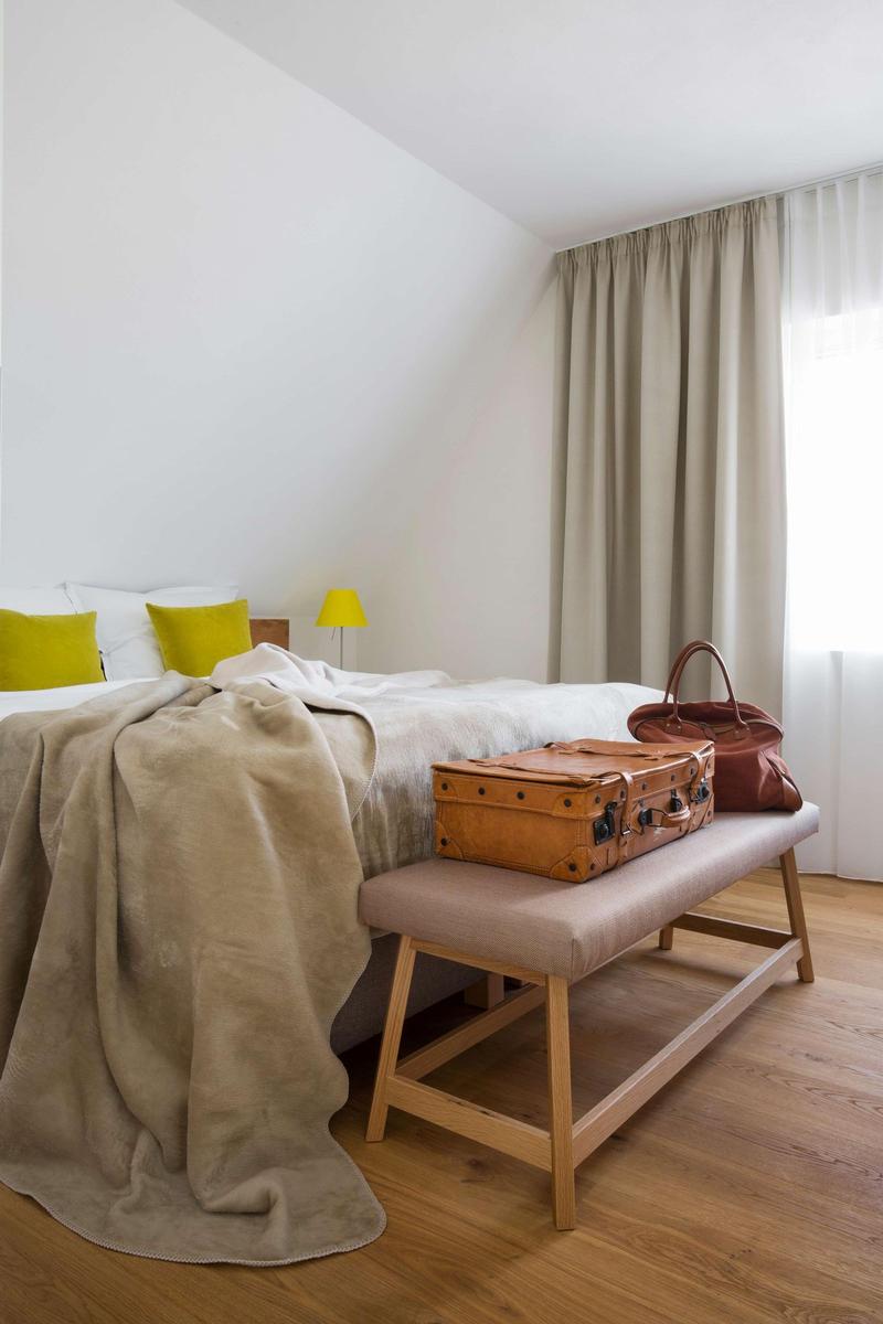 Bad mit runden Whirlpool-Badewanne, weißer Fliesenwand und Holzregal mit Handtüchern.