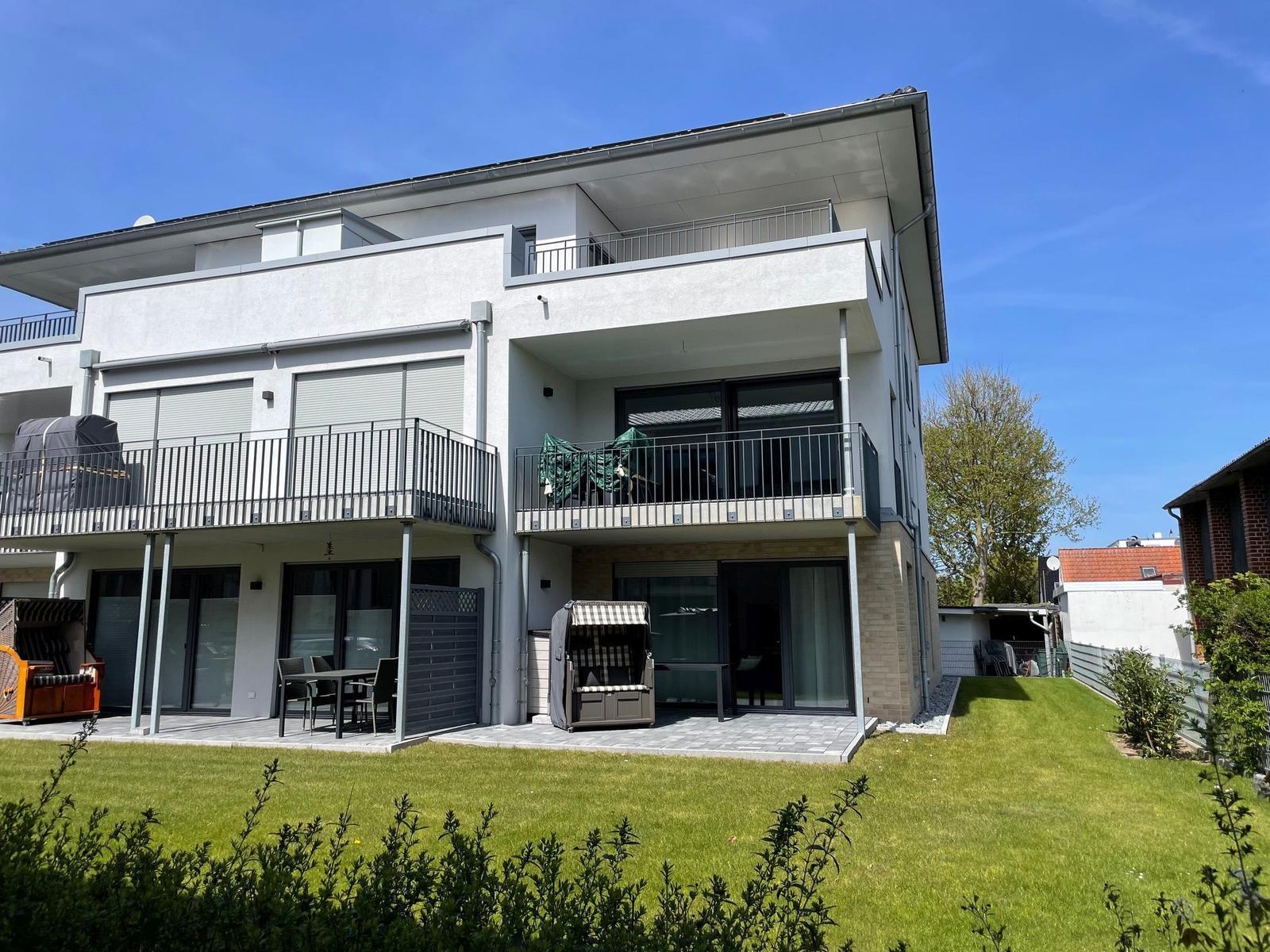Moderne Wohnung mit Balkon und Garten. Terrasse mit Sitzgelegenheit.