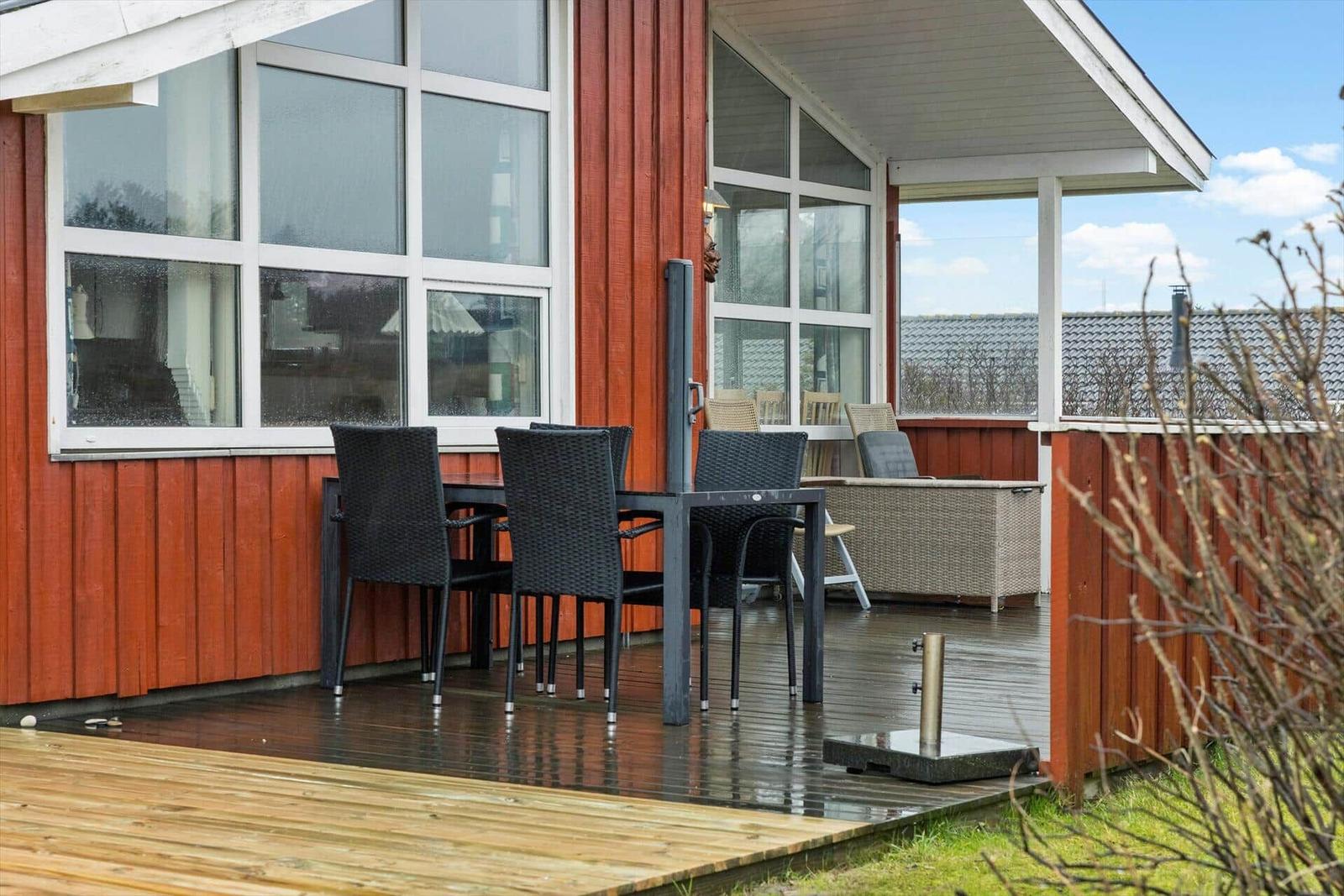 Rotes Holzhaus mit Dachgaube und Gartenweg. Hintergrund: Feld und Bäume.