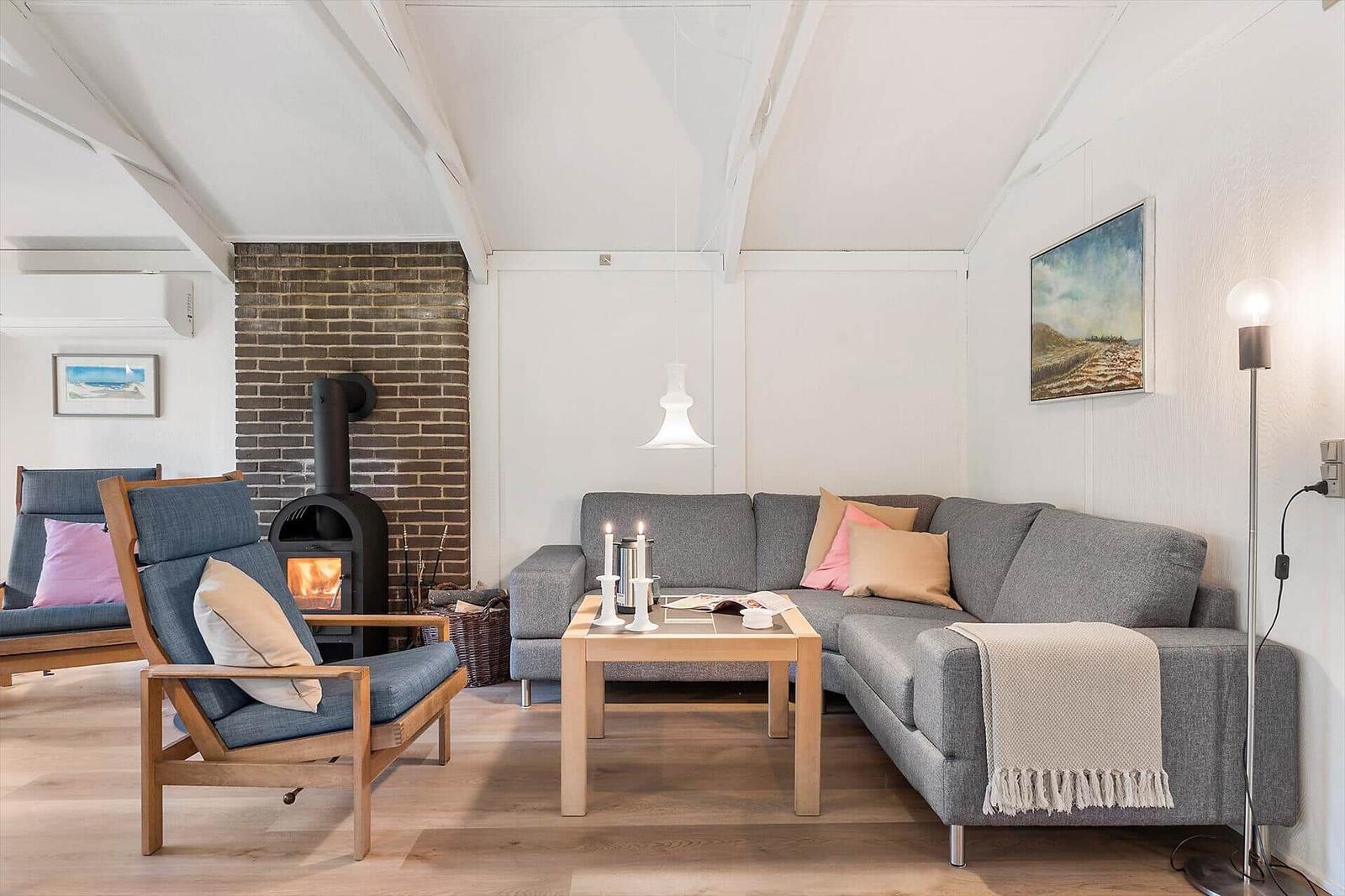 Schlafzimmer mit Bett, Wandbild und roter Tür. Blick in Wohnbereich mit Sofa.