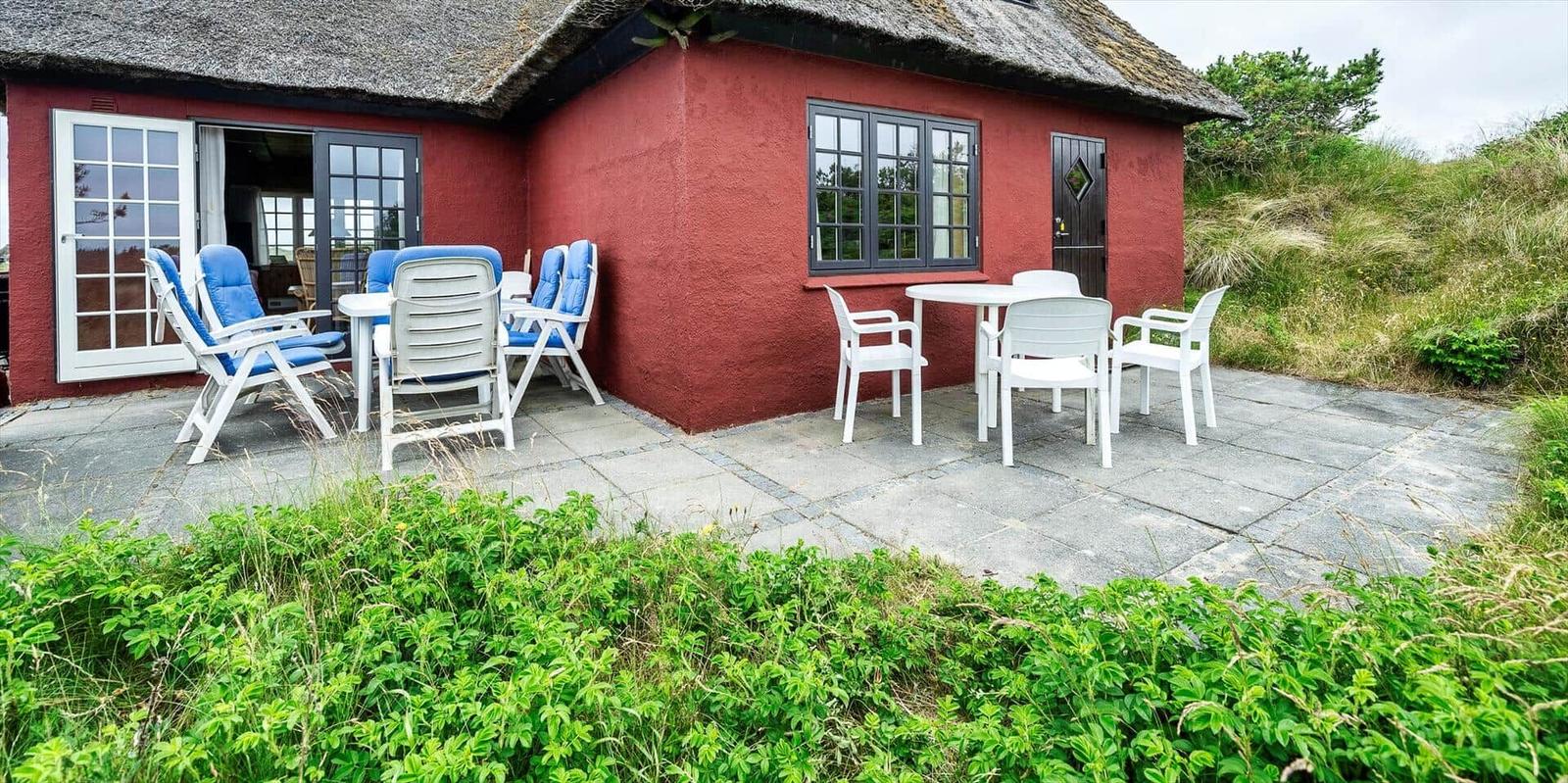 Zwei Betten mit weißer Bettwäsche, blaue Wand, Fenster mit Vorhang, Nachttisch und Bücherregal.