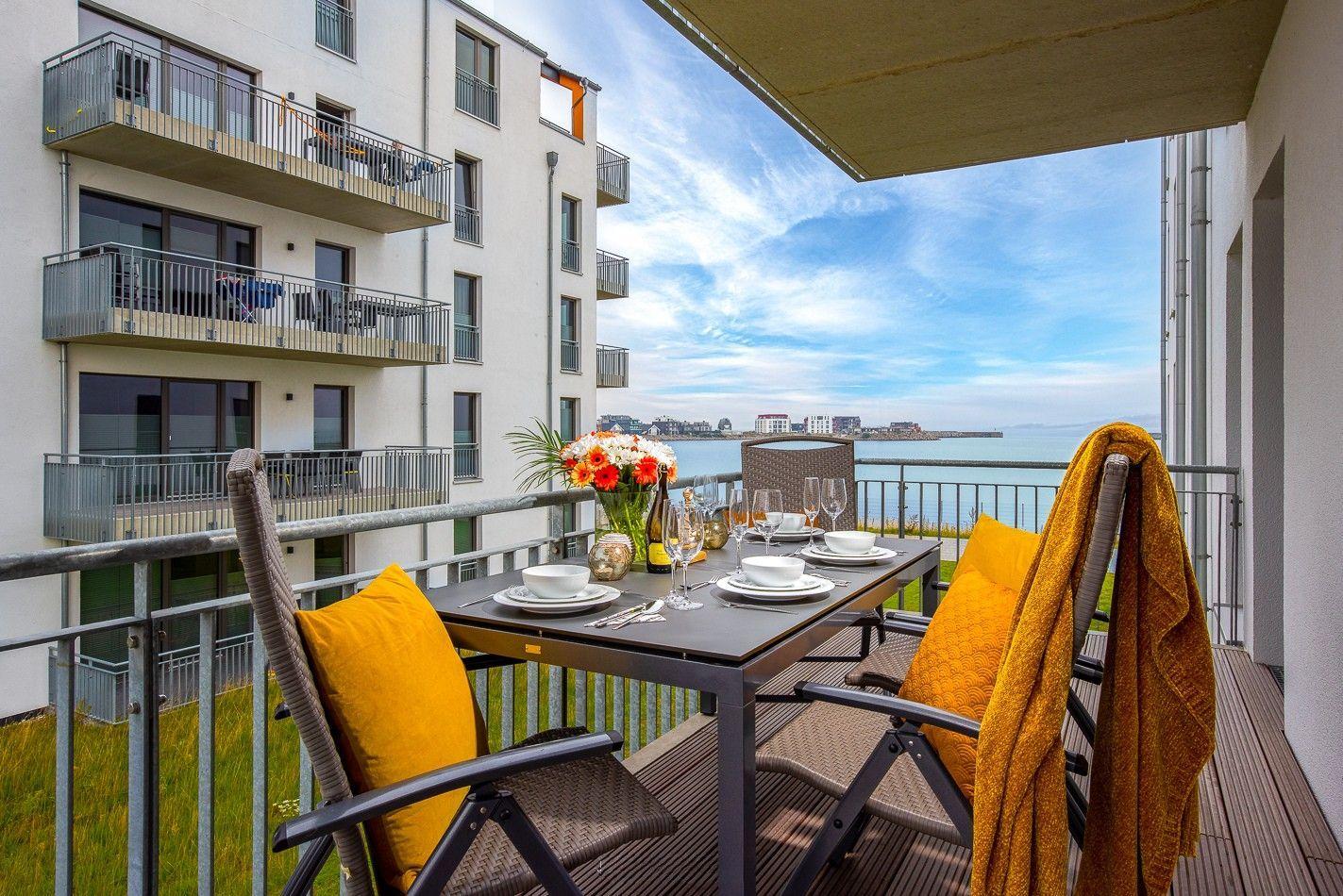 Schlafzimmer mit Bett, Wandfernseher und Fenster zum Balkon.