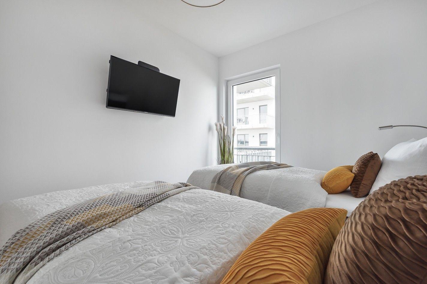Küche mit Arbeitsplatte, Fenster und Blick auf Balkon. Wohnzimmer mit Sofa und Holzboden sichtbar.