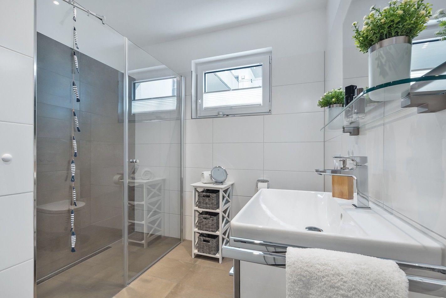 Moderne Küche mit weißen Schränken, dunklem Arbeitsplatz und Fenster zum Balkon.