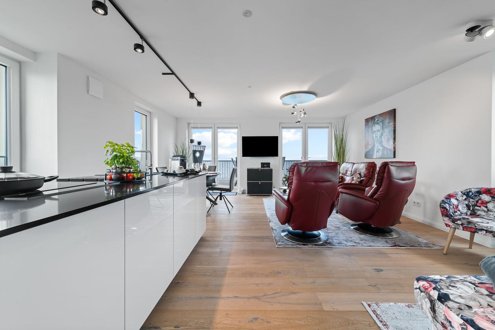 Moderne Küche mit Kücheninsel, Essbereich und Wohnzimmer mit Blick aufs Meer.