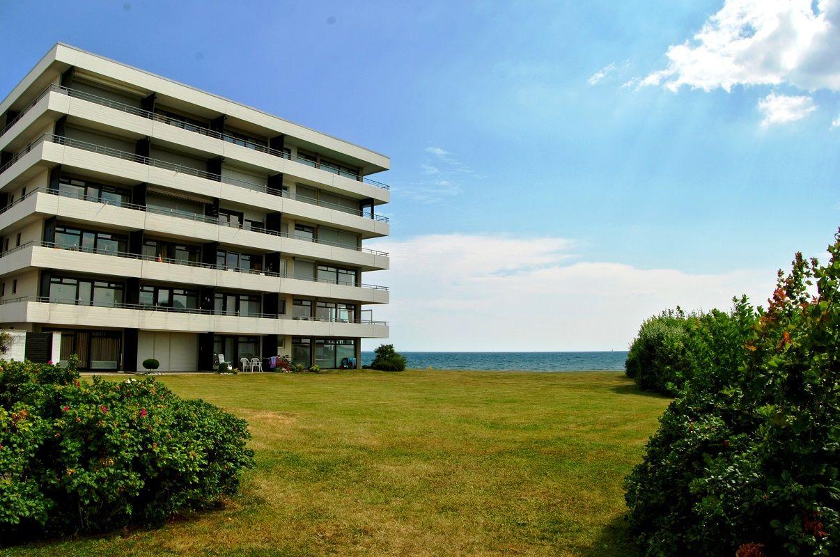 Wohn- und Essbereich mit Blick auf das Meer durch Glastüren.