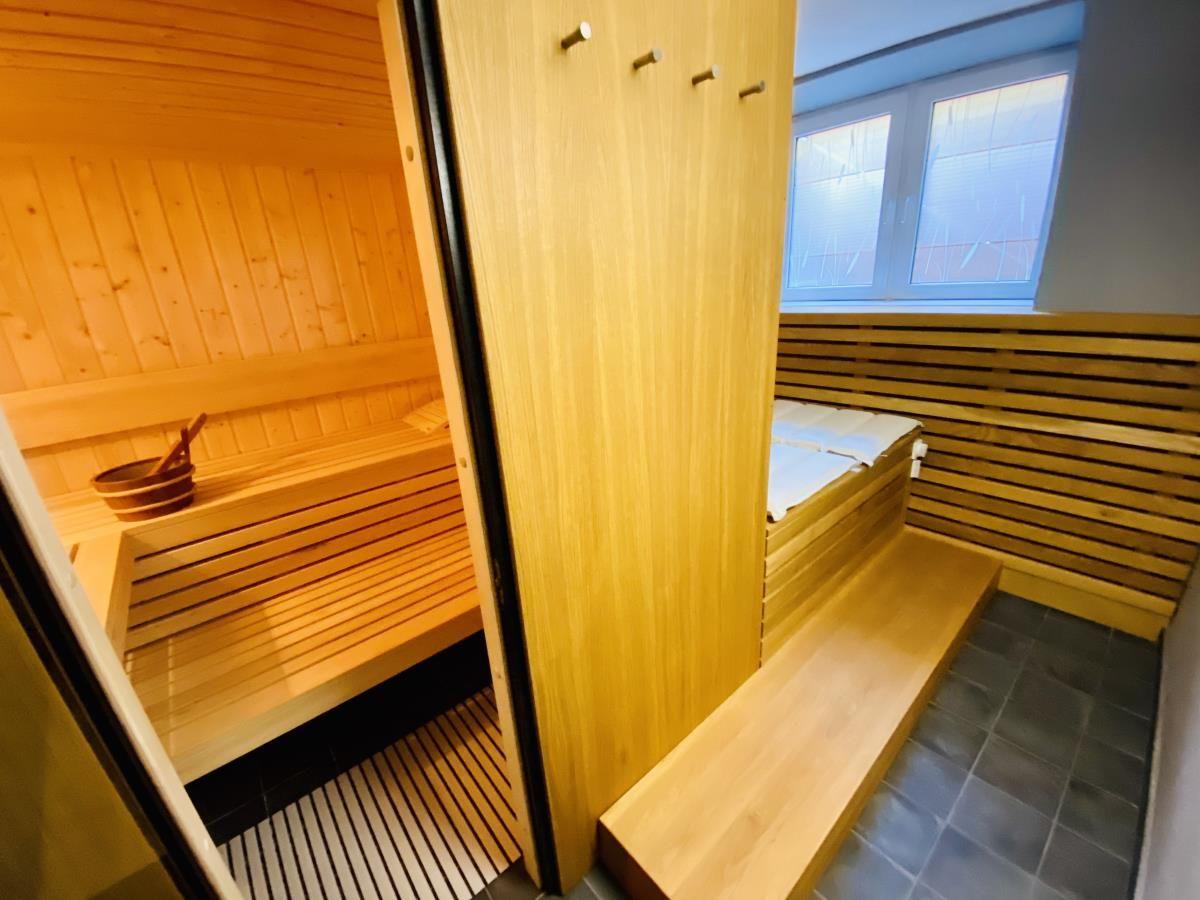 Sauna mit Holzbank, Holzwand und Holzschale mit Löffel.
