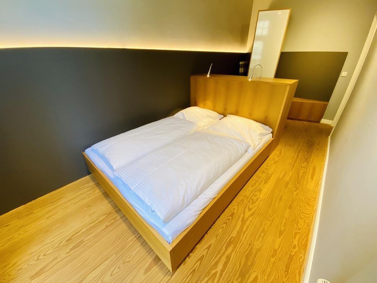 Flur mit Holzboden, Tür und Wandkarte. Willkommensmatte und Bilder an den Wänden.