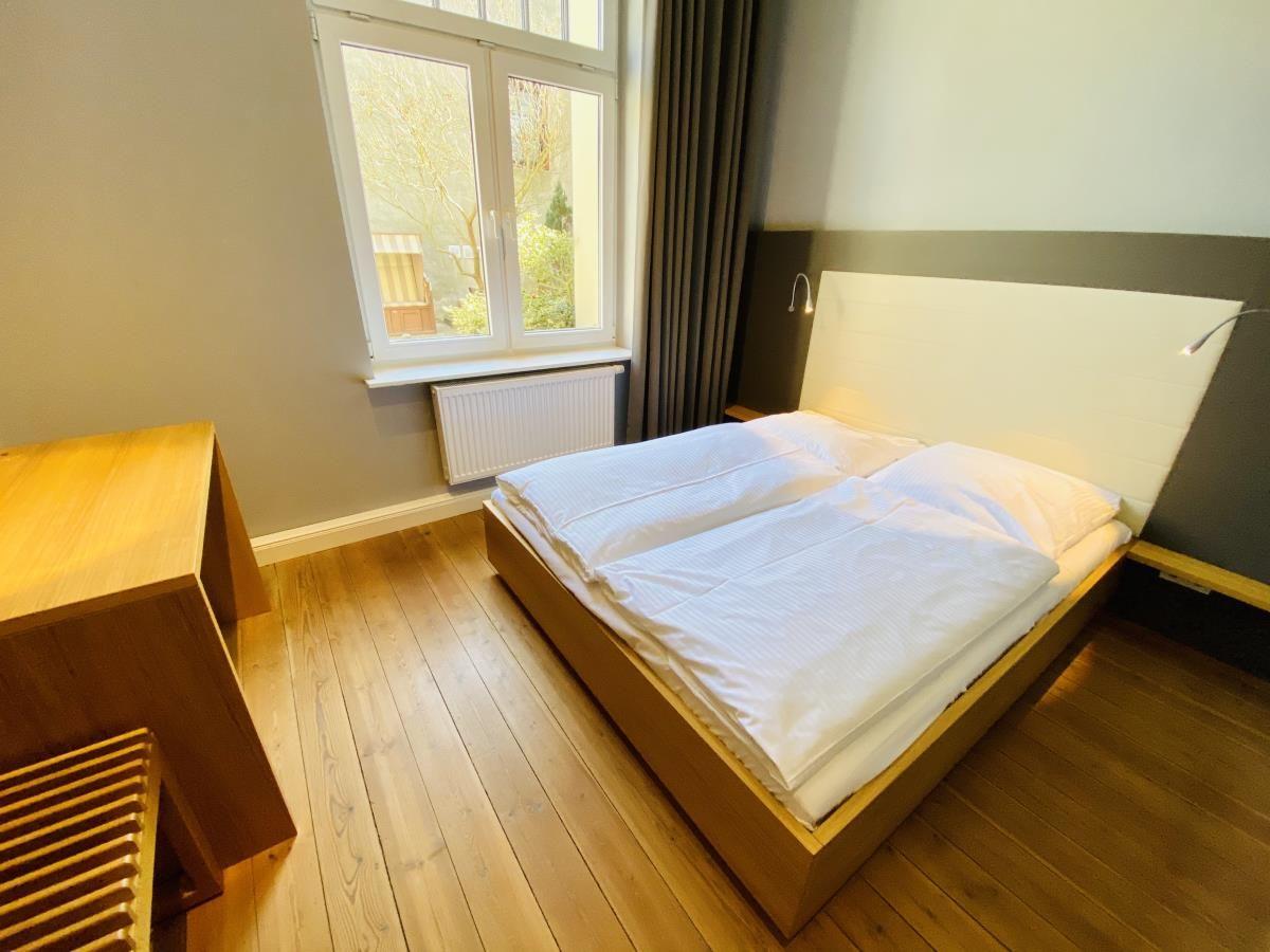 Ein Raum mit Holzbett und Sauna. Holzwände und weißes Bettlaken.
