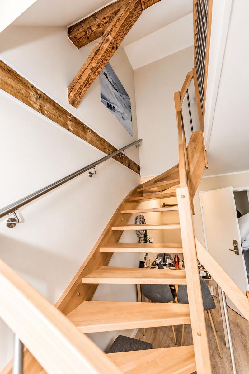 Apartment with sofa, table, chairs, and stairs to upper level.