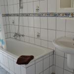 Badezimmer mit Badewanne, Waschbecken und Duschvorhang mit Fischmotiven.