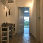 Flur mit Sitzbank, Kleiderhaken und Tür zum Balkon.