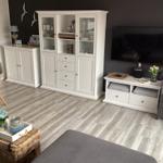 Wohnzimmer mit weißem Sideboard, Fernseher und Sitzgelegenheiten.