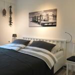 Schlafzimmer mit Bett, Wandbild und Stuhl.