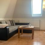 Wohnzimmer mit Sofa, Tisch und Fenster unter schrägen Dachdecken.