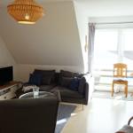 Wohnzimmer mit Sofa, Fernseher und Holztreppe zur oberen Etage.