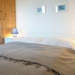 Schlafzimmer mit Bett, Nachttischen und Holzschrank an der Wand.