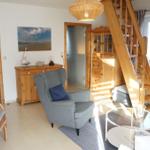 Wohnzimmer mit Holztreppe, Sessel und Glas-Tisch. Blick in Bad und Schlafzimmer.