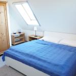 Schlafzimmer mit Dachschrägen, Bett, Kleiderschrank und Nachttisch.