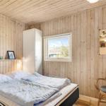 Schlafzimmer mit Holzwand, Bett, Stuhl und Fenster.