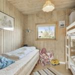 Ein Schlafzimmer mit Holzwand, Bett, Krippenbett, Fenster und Spielzeug.