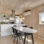 Küche mit Essbereich, Holzwand und -decke, weißer Arbeitsplatte und schwarzen Stühlen.