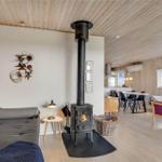Wohnraum mit Kaminofen, Sofa und Essbereich. Holzwände und -decke.