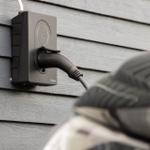 Elektrischer Ladeanschluss an Hauswand mit Stecker in Fahrzeug
