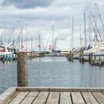 Hafen mit Booten und hölzernem Steg unter bewölktem Himmel