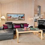Wohnzimmer mit Ledersofa, Holztisch und Küchenbereich im Hintergrund.