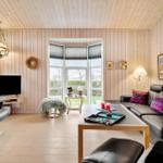 Wohnzimmer mit Holzwand, Sofa, Fernseher und Fensterblick.