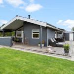 Moderne Ferienhaus mit Holzterrasse, Garten und Außensitzgelegenheiten.