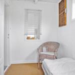 Ein Schlafzimmer mit Bett, Stuhl und Fenster. Wand und Boden sind weiß.