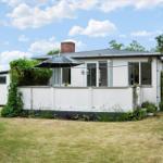 Weißes Haus mit Terrasse und Sonnenschirm im Garten