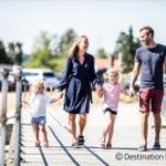 Eine Familie spaziert über eine hölzerne Brücke mit Metallgeländer.