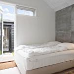 Schlafzimmer mit Bett, Fenster und Tür zum Außenbereich.