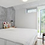 Schlafzimmer mit Bett, Kissen und Tür zum Garten.