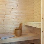 Sauna mit Holzbank, Handtuch und Eimer mit Besen.
