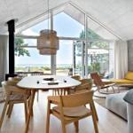 Ein Esszimmer mit Holztisch, Stühlen und Blick aufs Meer.
