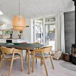 Essbereich mit Holztisch, Stühlen und Kaminofen. Durchgang zur Küche und Terrasse.