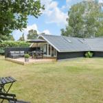 Modernes Haus mit Terrasse, Garten und Grillplatz unter blauem Himmel.