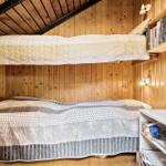 Zimmer mit Doppelbett und oberem Bett, Holzwände und Regal mit Büchern.