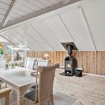 Haus mit Essbereich, Kamin und Holzwand. Holzfußboden und weißer Deckenrahmen.